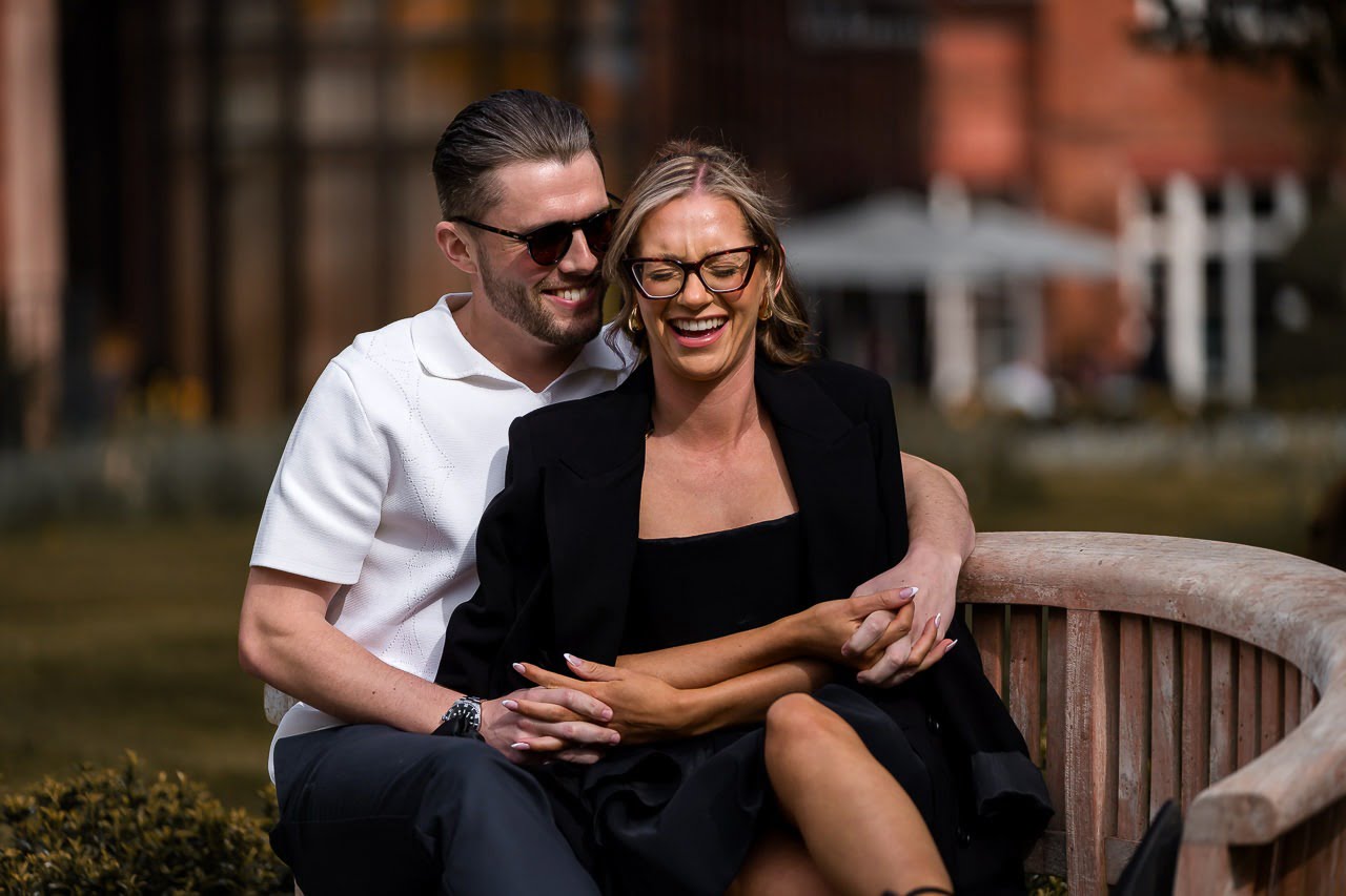 couple sitting on a wooden bench for a spring engagement shoot