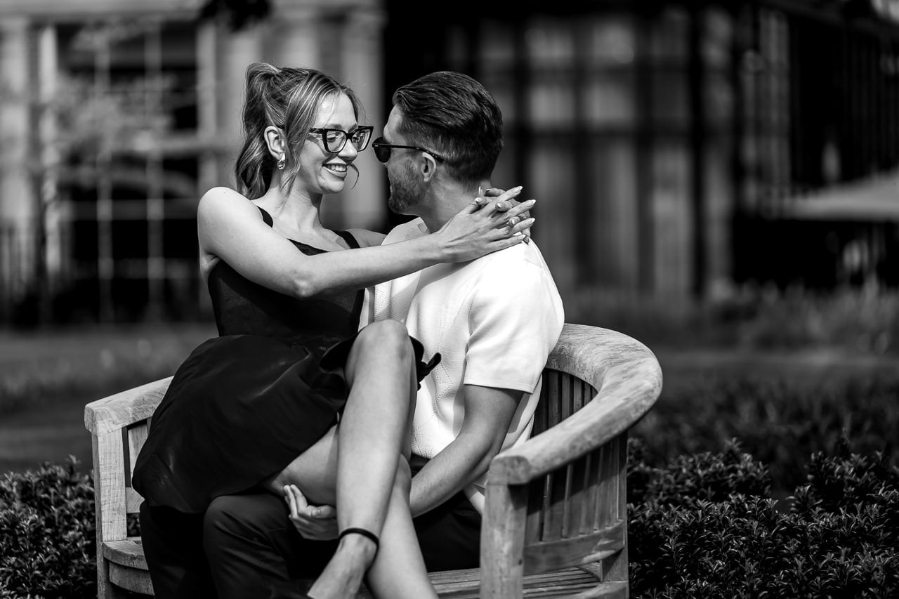 black and white photo of an engaged couple sitting on a wooden bench for a spring engagement shoot at the Grove Hotel