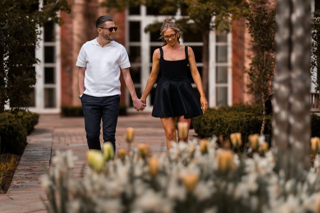 couple walk through the gardens at the grove hotel for the spring engagement