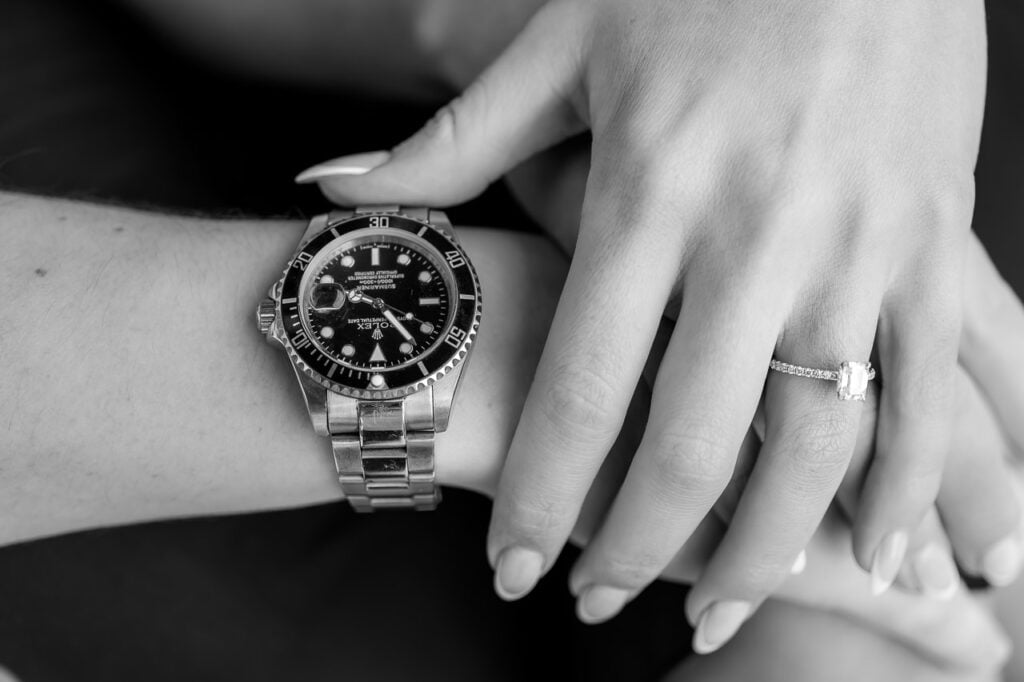 black and white photo of the couple's hands show his watch and her diamond engagement ring for the engagement shoot