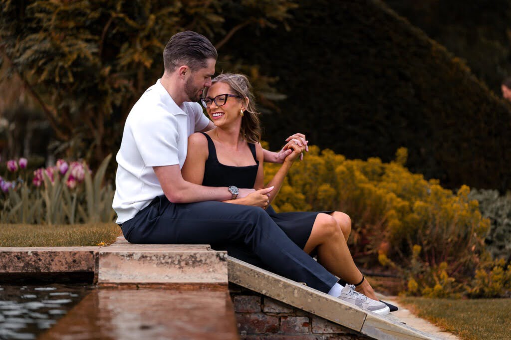 man and woman sitting by the side of a waterfall and fountain in the garden of the Grove Hotel