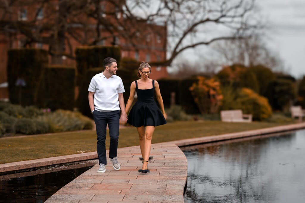 couple walking along a pathway through the water in the gardens of the grove