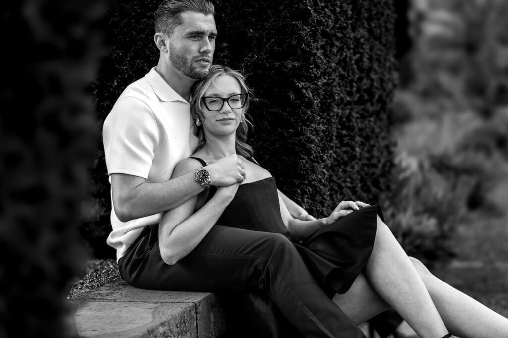 black and white photo of a couple sitting on a step with a woman leaning back on the man