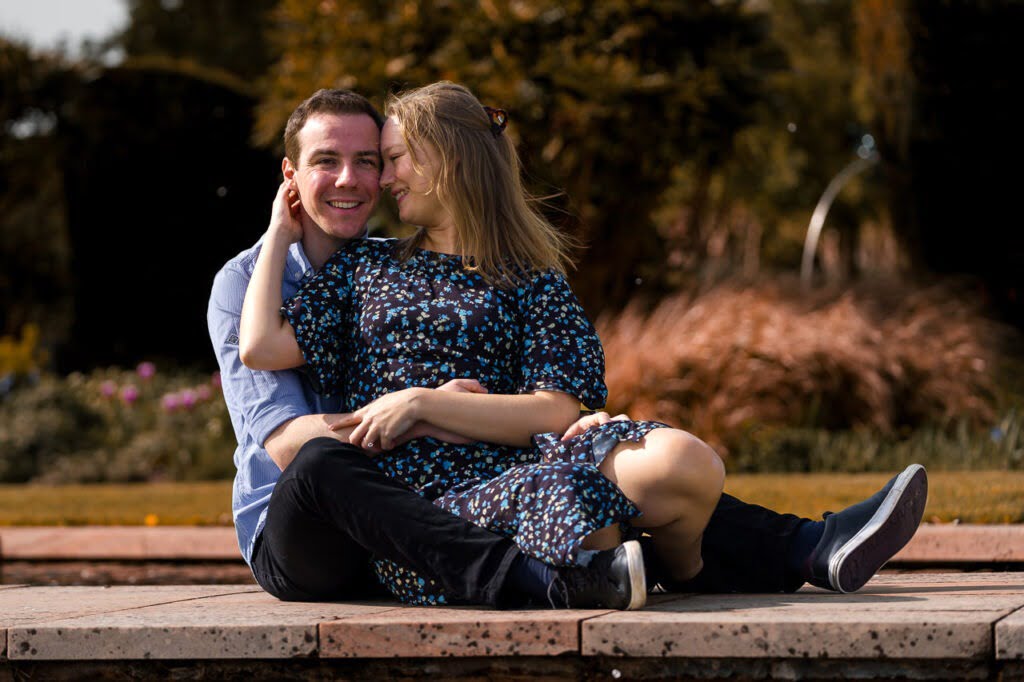 man and woman sitting on a payment by some water