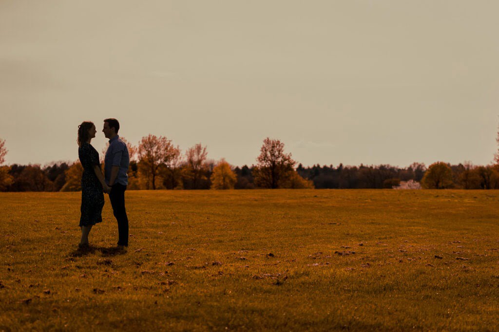 spring engagement session and couple facing each other with the sunset in the background