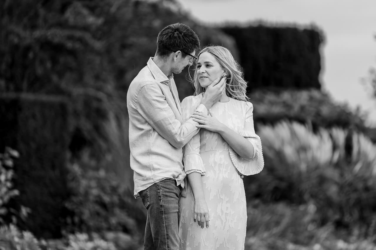 man and woman facing each other, the man has his hand cupping the woman's face at their summer engagement session