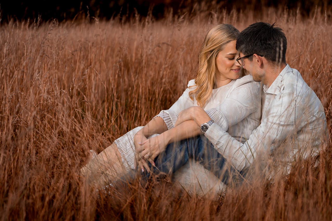 couple laying on to each other in the tall golden grasses