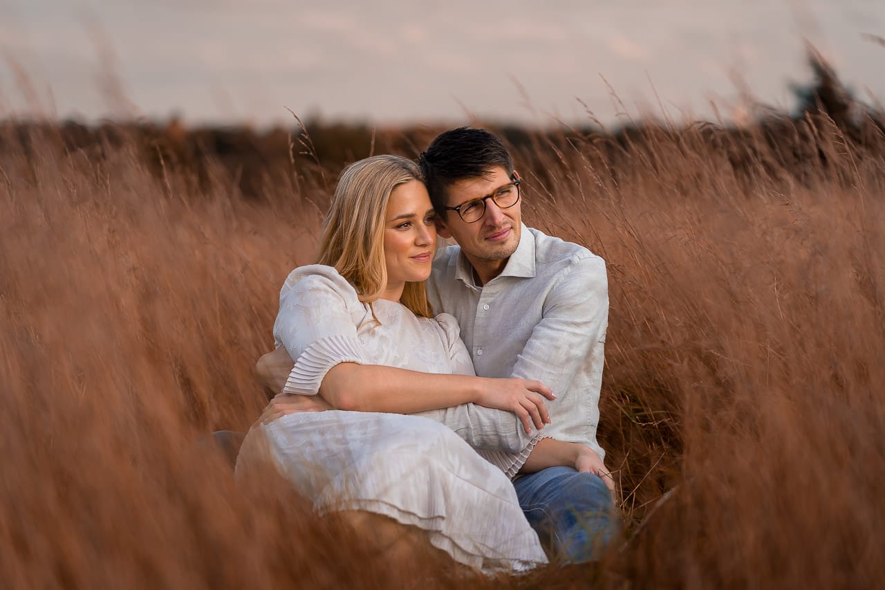 couple laying on to each other in the tall golden grasses