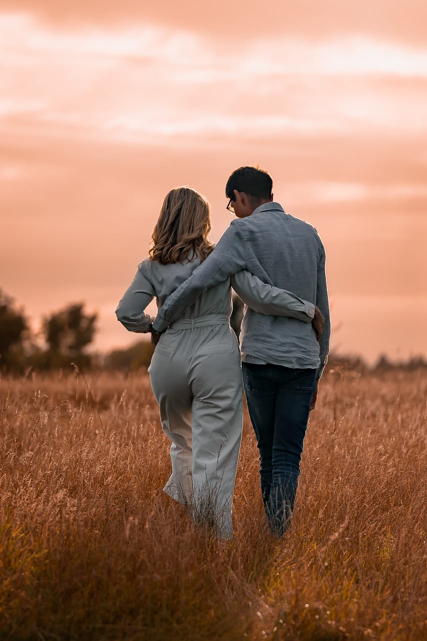 engaged couple walking with arms around each other into the sunset for their summer engagement session