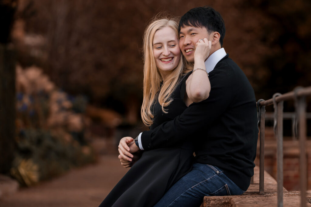 couple sitting together on a wall and laughing at each other